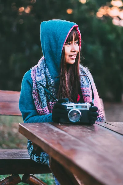 Young female photographer in cold weather wearing sweater and colorful scarf during afternoon sunset outside — Stock Photo, Image