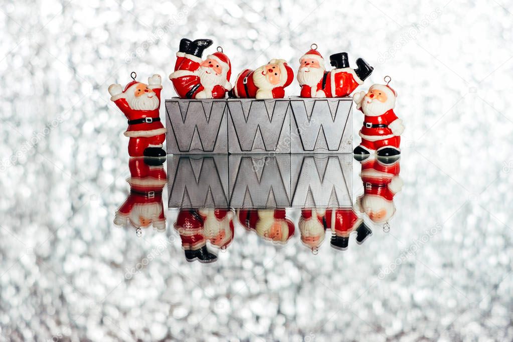 Small Santas decorations on silver shiny background with www letters