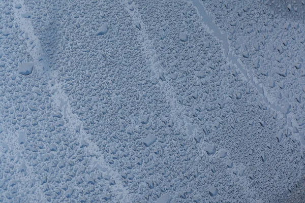 Grandes gotas de chuva em um capô de carro, a textura da tinta é azul metálico, azul abstrato bokeh fundo — Fotografia de Stock