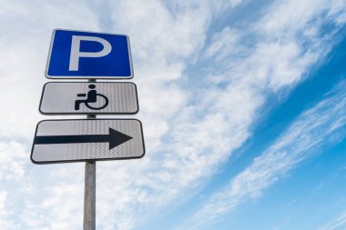 Yer, doğru tabela, bir yer işareti mavi gökyüzü beyaz bulutlar, arka plan ile karşı Engelli otopark trafik işaretleri ile metal destek