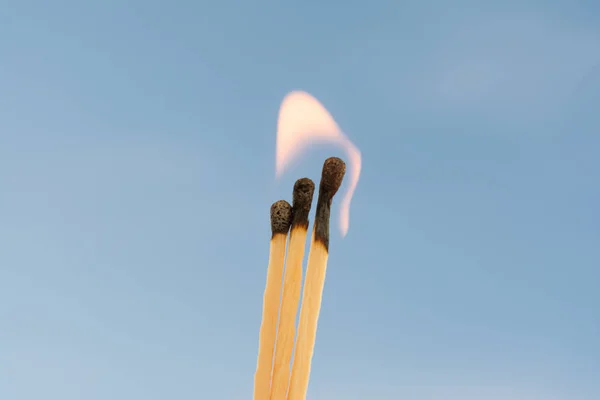Three burning matches on a blue background — Stock Photo, Image