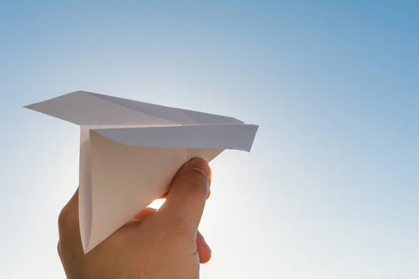 La mano sostiene el plano de papel blanco en el cielo azul — Foto de Stock