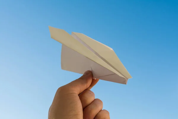 La mano sostiene el plano de papel blanco en el cielo azul — Foto de Stock