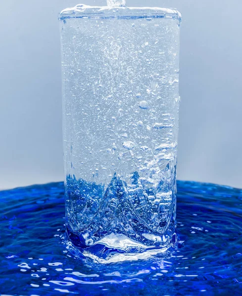 Um copo de água, água com bolhas transborda através de vidro — Fotografia de Stock