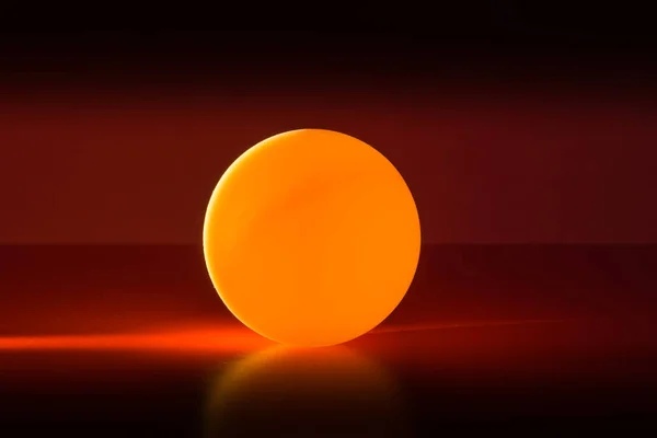 Yellow ball on a red dark background illuminated by a side beam of light — Stock Photo, Image