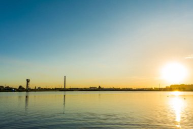 Ufuk akşam gökyüzü ve su yüzeyine böler. Yaz aylarında günbatımı.