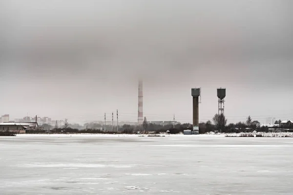 연못은 지평선 높은 산업 건설, 우울한 흐린 날씨에 얼음으로 덮여 — 스톡 사진