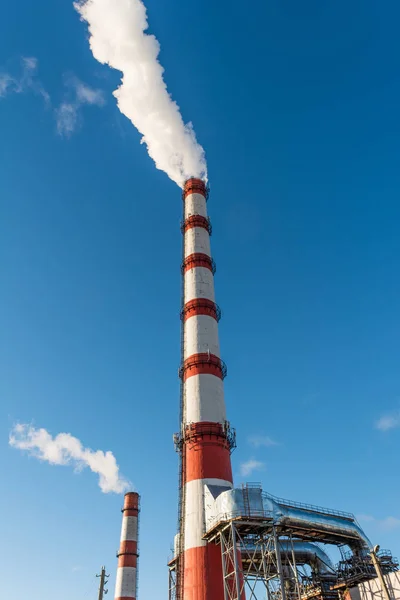 Centrale combinata di calore ed energia elettrica, dalla pipa va fumo bianco su uno sfondo di cielo blu puro — Foto Stock