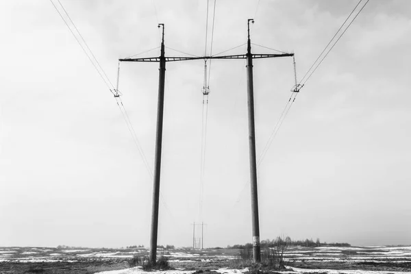 Zwei Stahlbetonmasten der Hochspannungsleitung im Vordergrund und viele Hochspannungsmasten im Hintergrund, die durch Drähte verbunden sind — Stockfoto