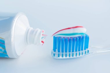 Mavi kıllar ile net plastik diş fırçası, bir tüp dışında beyaz mavi kırmızı diş macunu sıkar