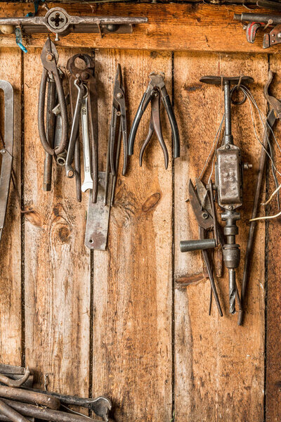 old working tool on the background of wooden panels, the tools of the artisan hang on nails
