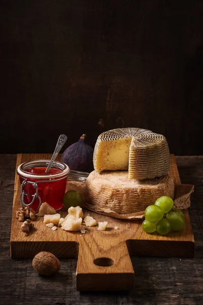 Escura ainda vida com tábua de queijos, frutas e vinho — Fotografia de Stock