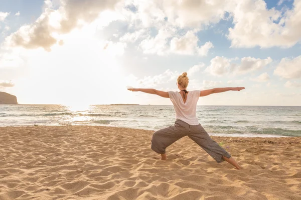 Mulher praticando ioga na praia do mar ao pôr do sol. — Fotografia de Stock