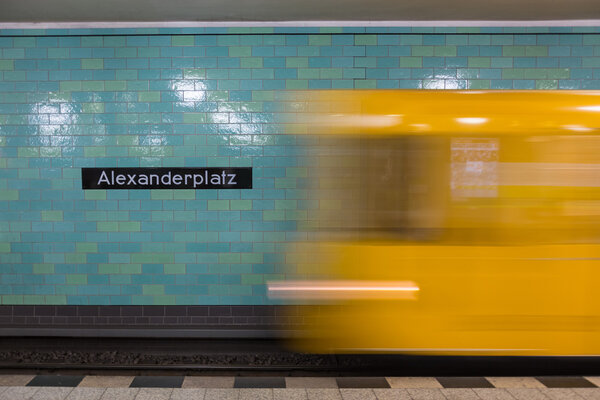 Yellow subway train in motion on Berlin Alexanderplatz underground station.