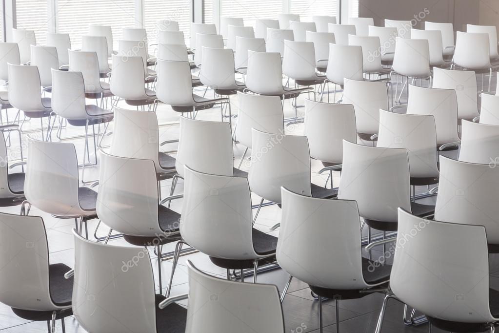 Empty white chairs in contemporary conference hall with