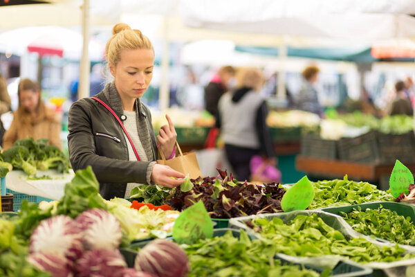 Woman buying vegetable at local food market.