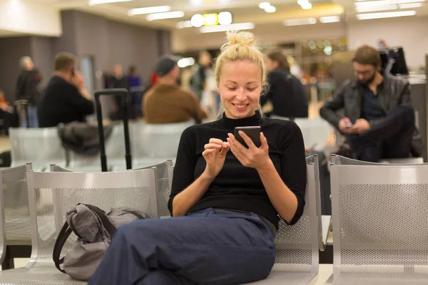 Señora usando el teléfono inteligente mientras espera en las puertas de salida del aeropuerto . —  Fotos de Stock