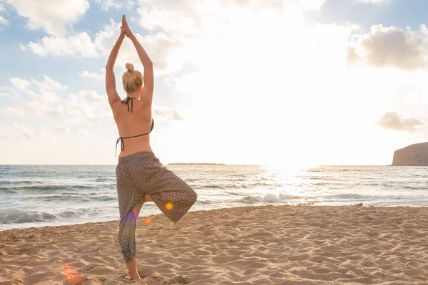 Mulher praticando ioga na praia do mar ao pôr do sol. — Fotografia de Stock