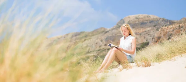 Frau liest Buch, genießt Sonne am Strand. — Stockfoto