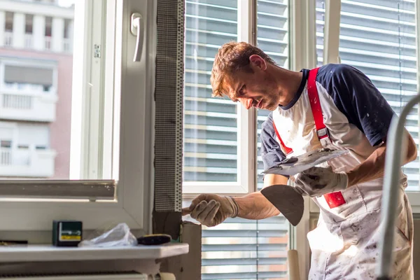 Yesero renovando paredes y techos interiores. Trabajos de acabado . — Foto de Stock