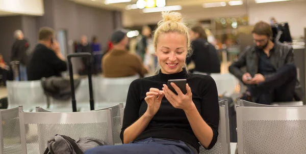 Señora usando el teléfono inteligente mientras espera en las puertas de salida del aeropuerto . —  Fotos de Stock