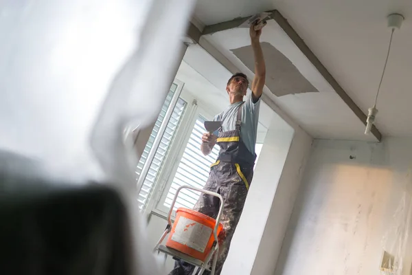 Yesero renovando paredes y techos interiores. Trabajos de acabado de construcción . — Foto de Stock