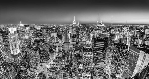 New York City. Manhattan downtown skyline with illuminated Empire State Building and skyscrapers at dusk. Black and white image. Panoramic composition.