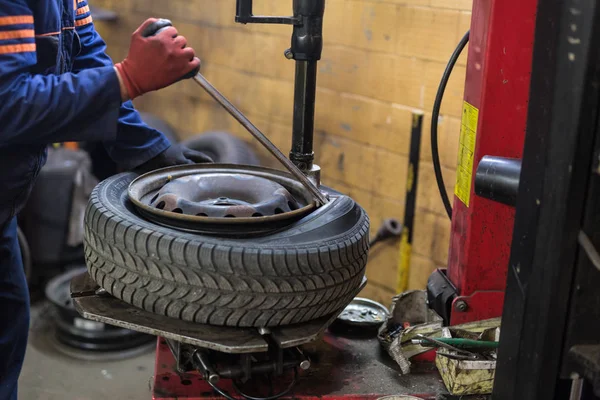 Mécanicien automobile professionnel remplaçant le pneu sur la roue dans le service de réparation automobile. — Photo
