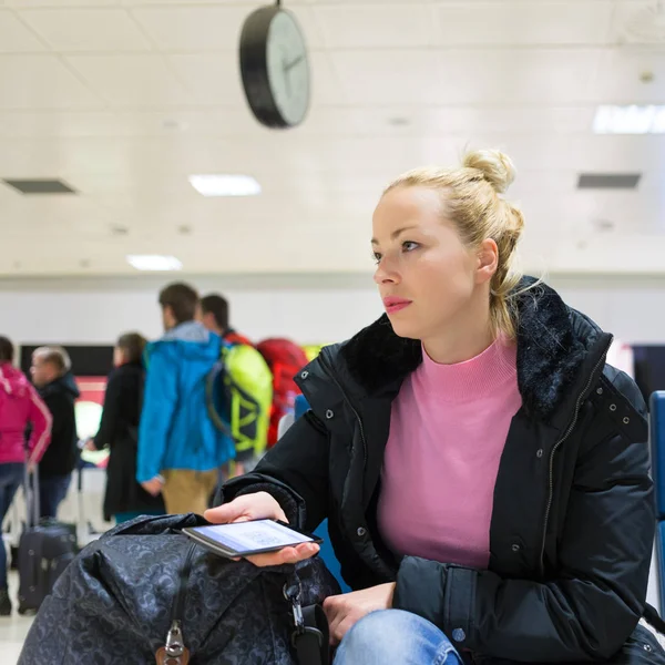 Señora usando el teléfono inteligente mientras espera en las puertas de salida del aeropuerto . — Foto de Stock