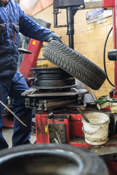 Mecánico automático profesional que reemplaza el neumático en la rueda en el servicio de reparación de automóviles. — Foto de Stock