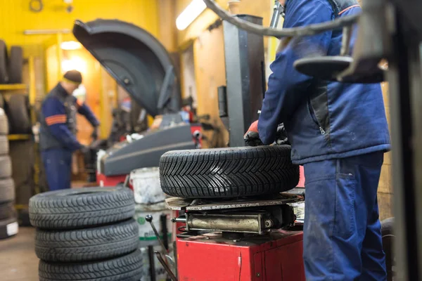 Profesionální automechanik Výměna pneumatiky na kolečkách v autoservisu. — Stock fotografie
