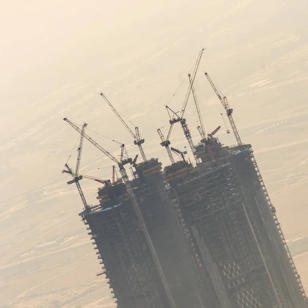 Estaleiro de construção de arranha-céus com guindastes em cima de edifícios . — Fotografia de Stock