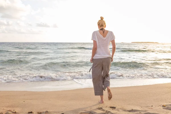 Mujer caminando en la playa de arena a la hora dorada —  Fotos de Stock
