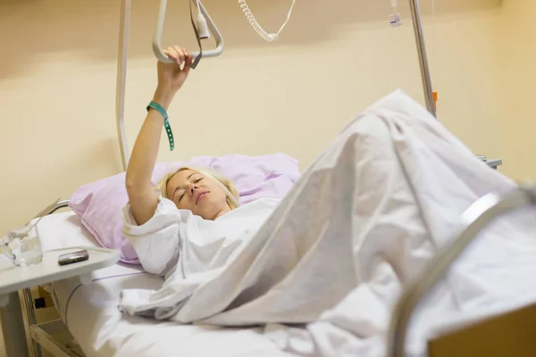 Bedridden female patient recovering after surgery in hospital care. — Stock Photo, Image