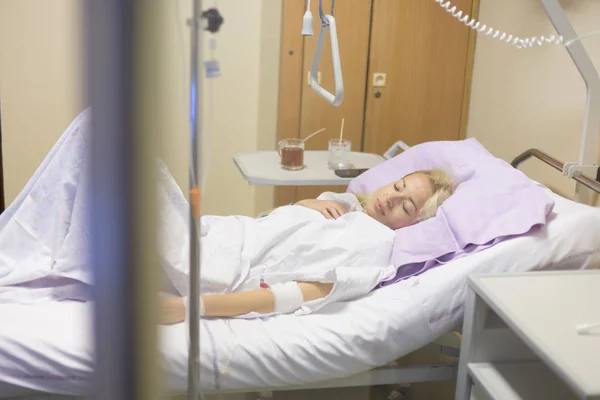 Sängliggande kvinnliga patienten återhämtar sig efter kirurgi i slutenvård. — Stockfoto