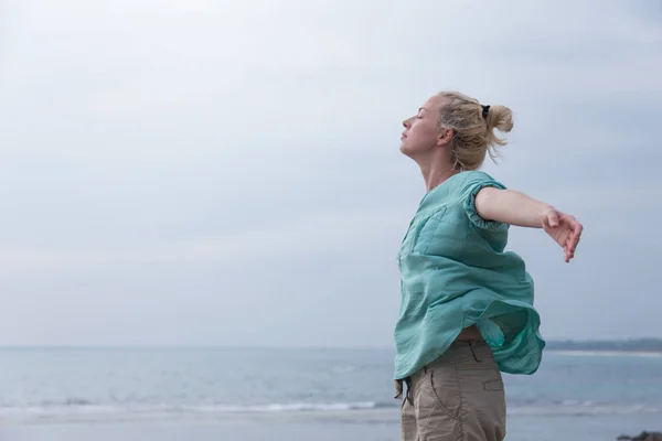 Donna libera godendo tempo ventoso sulla spiaggia il giorno nuvoloso — Foto Stock