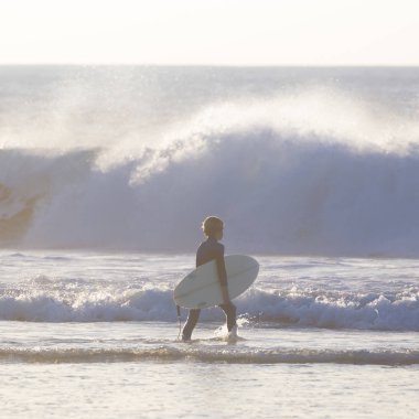 Sörfçü surfboard ile sahilde.