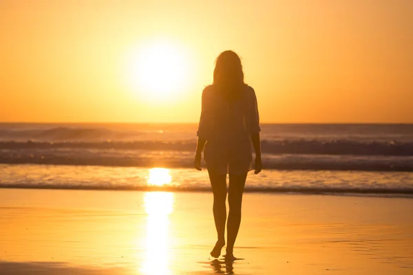 Lady lopen op het zandstrand in de zonsondergang. — Stockfoto