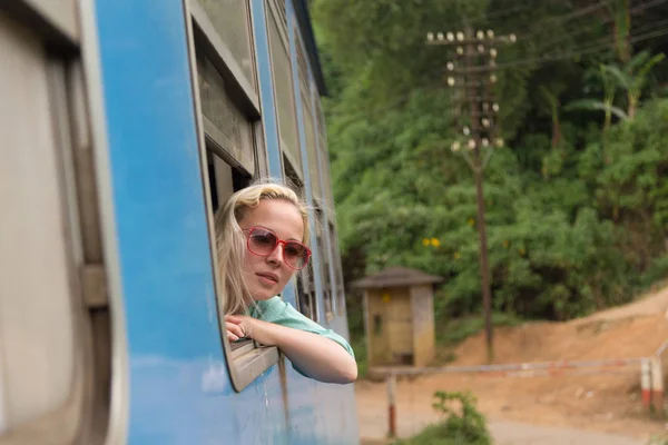 Blonde caucasian woman riding a train, looking trough window.