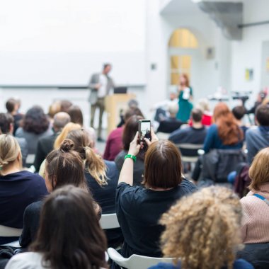 Üniversitedeki konferans salonunda sunum yapan adam.