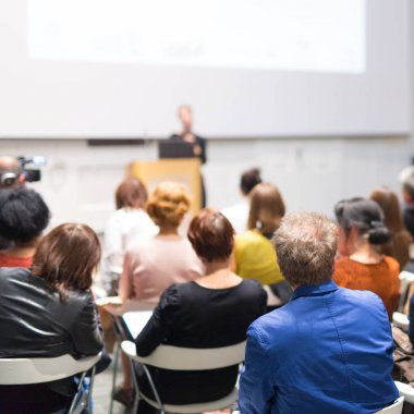 Üniversitedeki konferans salonunda sunum yapan kadın..