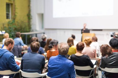 Üniversitedeki konferans salonunda sunum yapan kadın..