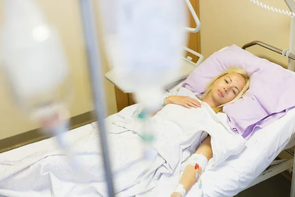 Bedridden female patient recovering after surgery in hospital care. — Stock Photo, Image