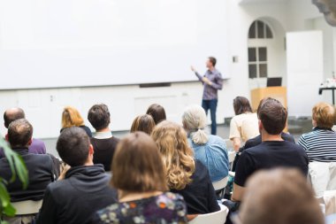 Üniversitedeki konferans salonunda sunum yapan adam.