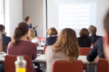 Üniversitedeki konferans salonunda sunum yapan kadın..