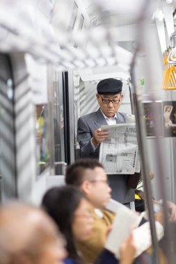Japon işadamı alarak ride içinde toplu taşıma ayakta ve gazete okuma sabah işe.