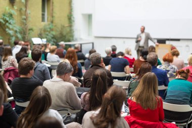 Üniversitedeki konferans salonunda sunum yapan adam.