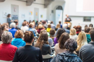 Üniversitedeki konferans salonunda sunum yapan adam.