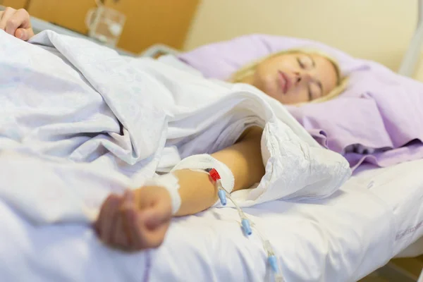 Bedridden female patient recovering after surgery in hospital care. — Stock Photo, Image