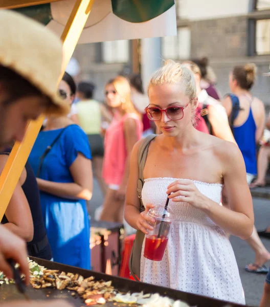 Vrouw koopt maaltijd in straatvoedsel festival. — Stockfoto